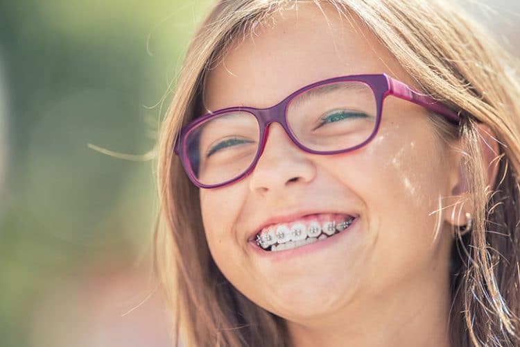 Portrait of a happy smiling teenage girl with dental braces and glasses.