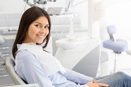 Brunette female patient sitting on dentistry chair and smiling